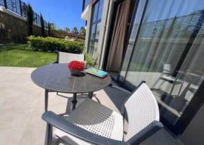 An outdoor patio with a round table, two chairs, a potted plant, and a book. - Ulu Residence Alanya (Alanya)