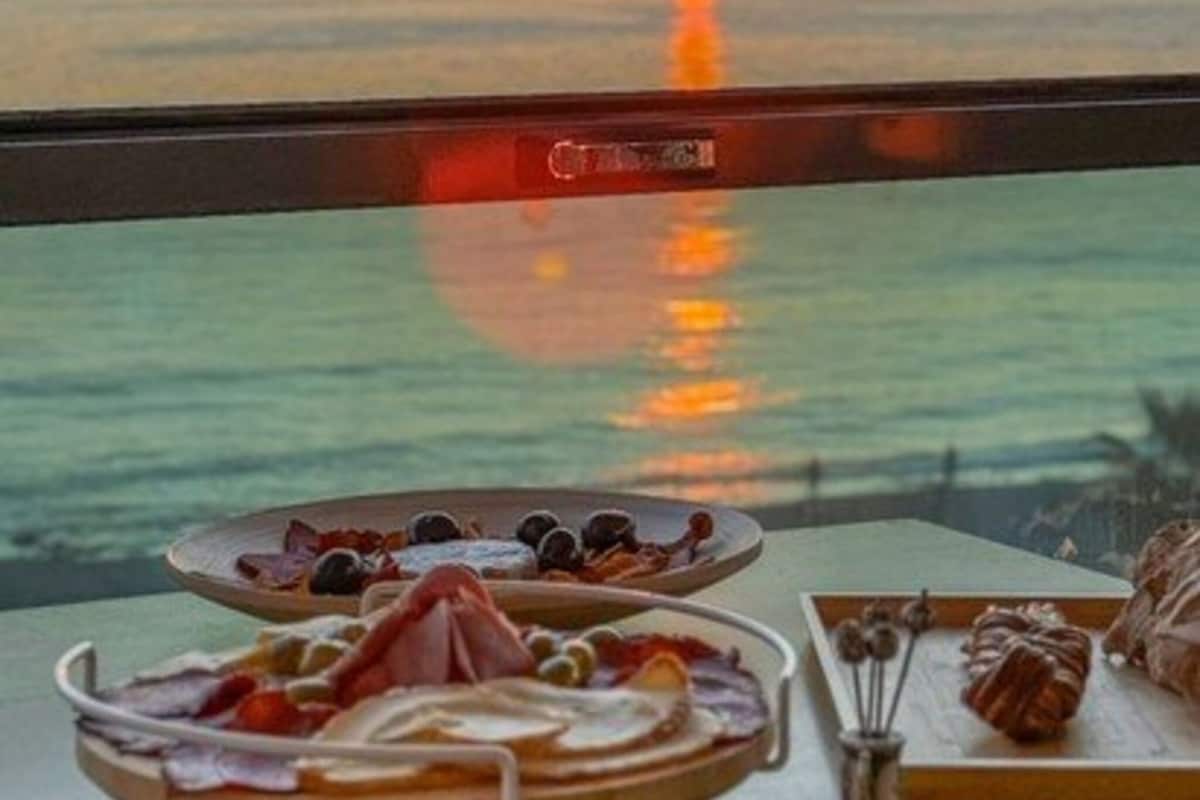 A table with food and a view of the sunset over the water.