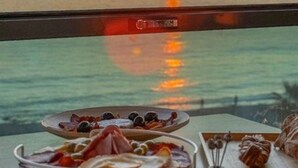 Una mesa con comida y vistas a la puesta de sol sobre el agua.