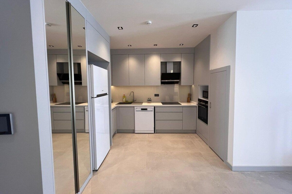 A modern kitchen with white cabinets, a dishwasher, a stove, and a microwave.