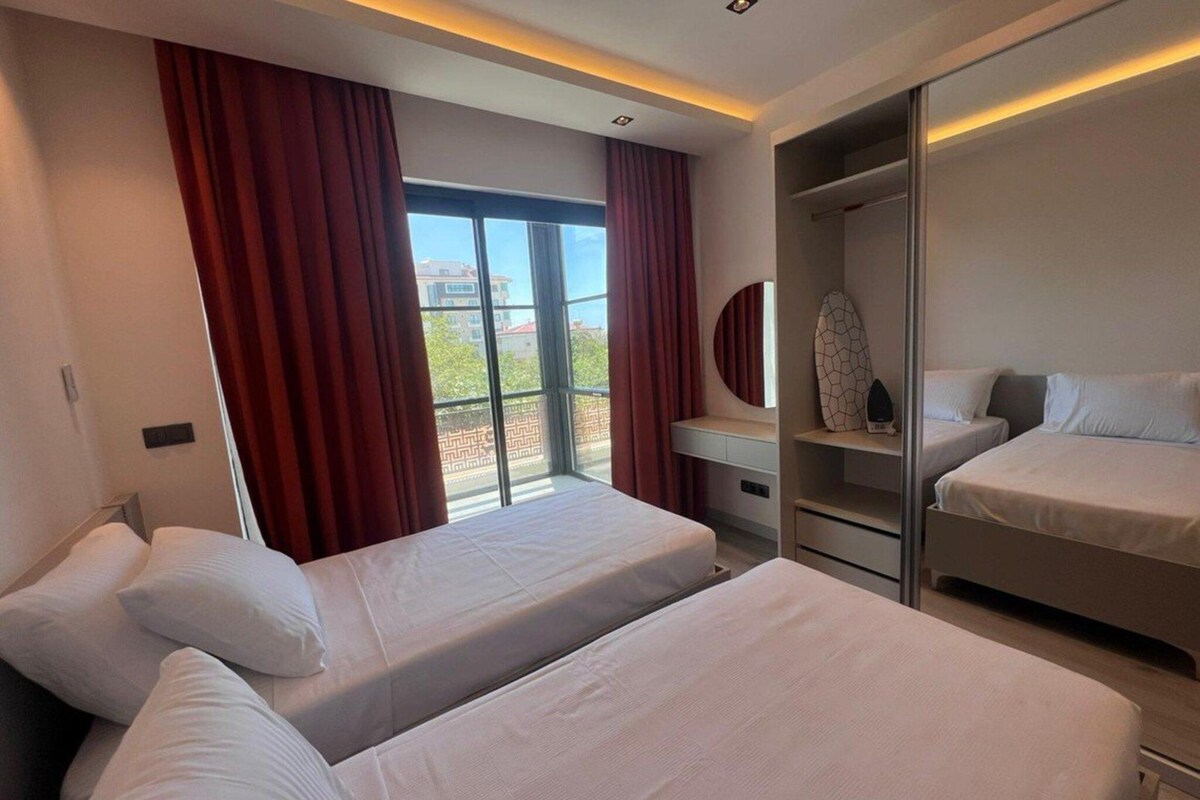 A hotel room with two beds, a desk, and a wardrobe.