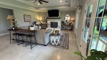 A spacious living area with a bar, seating, a fireplace, and a television.