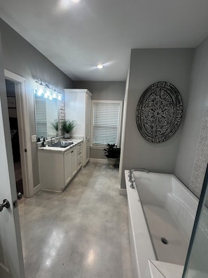 Un bagno con una vasca, un mobile lavabo e un grande specchio illuminato.