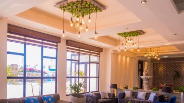 A spacious living area with a sofa set, armchairs, and a coffee table. Large windows provide natural light and views of the outside. - Hotel Presidente Premium Salinas (Salinas)