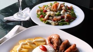 Two plates of food on a table with a glass of red wine. - Hotel Presidente Premium Salinas (Salinas)