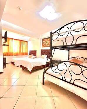 A hotel room with a bunk bed, two single beds, a flat-screen TV, and a large window with curtains. - Hotel Presidente Premium Salinas (Salinas)