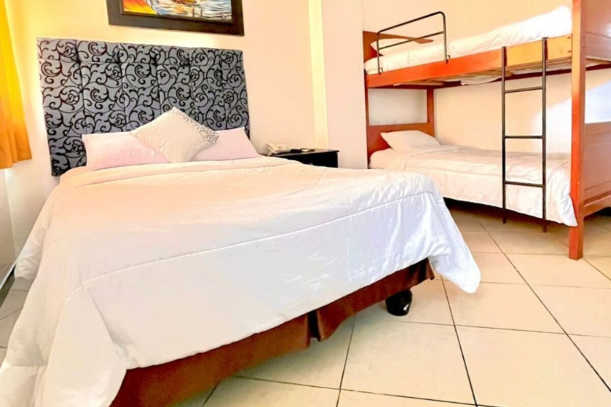 A hotel room with a large bed, a smaller bed, a bunk bed, and a painting on the wall.