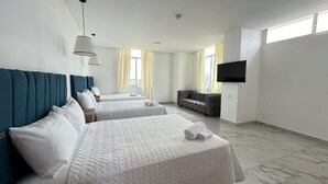 A hotel room with two beds, a sofa, a flat-screen TV, and large windows with curtains. - Hotel Presidente Premium Salinas (Salinas)