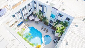 An aerial view of a hotel courtyard with a swimming pool, sun loungers, palm trees, and outdoor seating areas. - Hotel Presidente Premium Salinas (Salinas)