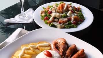 Two plates of food on a table with a glass of red wine.