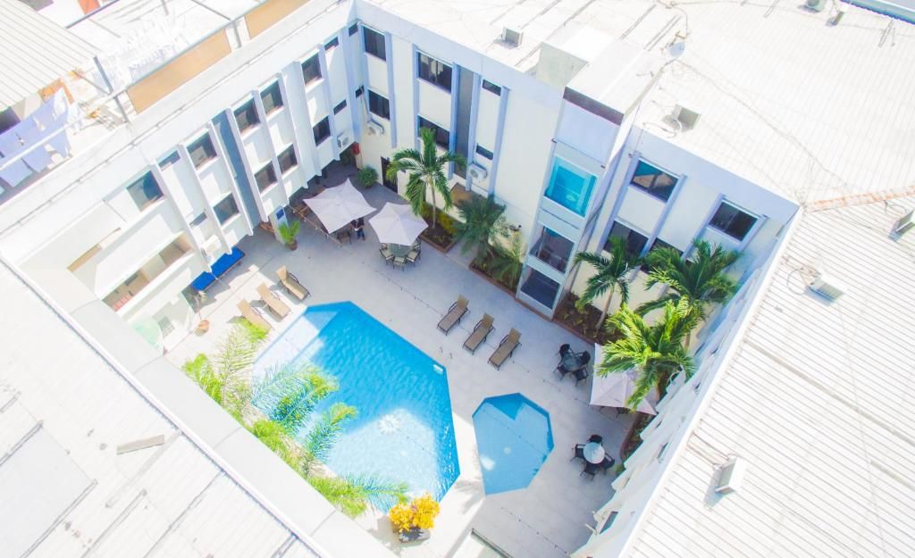 An aerial view of a hotel courtyard with a swimming pool, sun loungers, palm trees, and outdoor seating areas.