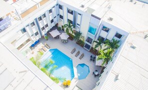 An aerial view of a hotel courtyard with a swimming pool, sun loungers, palm trees, and outdoor seating areas. - Hotel Presidente Premium Salinas (Salinas)