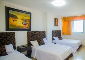A hotel room with two beds, a nightstand, a painting of a sunset over water, and a window with curtains.