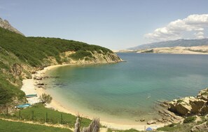 A coastal landscape with a clear beach, rocky cliffs, and a calm sea. - Beautiful home in Pag (Pag)