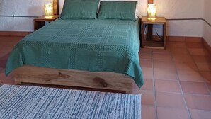 A bedroom with a bed, two nightstands, a wooden bench, and a window. - Cozy cabin in charming Jardin with WiFi (Jardin)