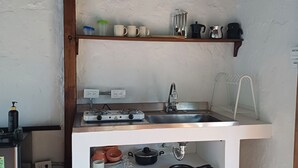 A compact kitchen with a white countertop, a sink, a stove, and a hanging light fixture. - Cozy cabin in charming Jardin with WiFi (Jardin)