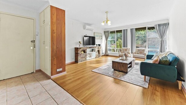 A spacious living room with a wooden floor, a TV, a fireplace, and a large window with curtains. - Retro Retreat - Mornington (Mornington)