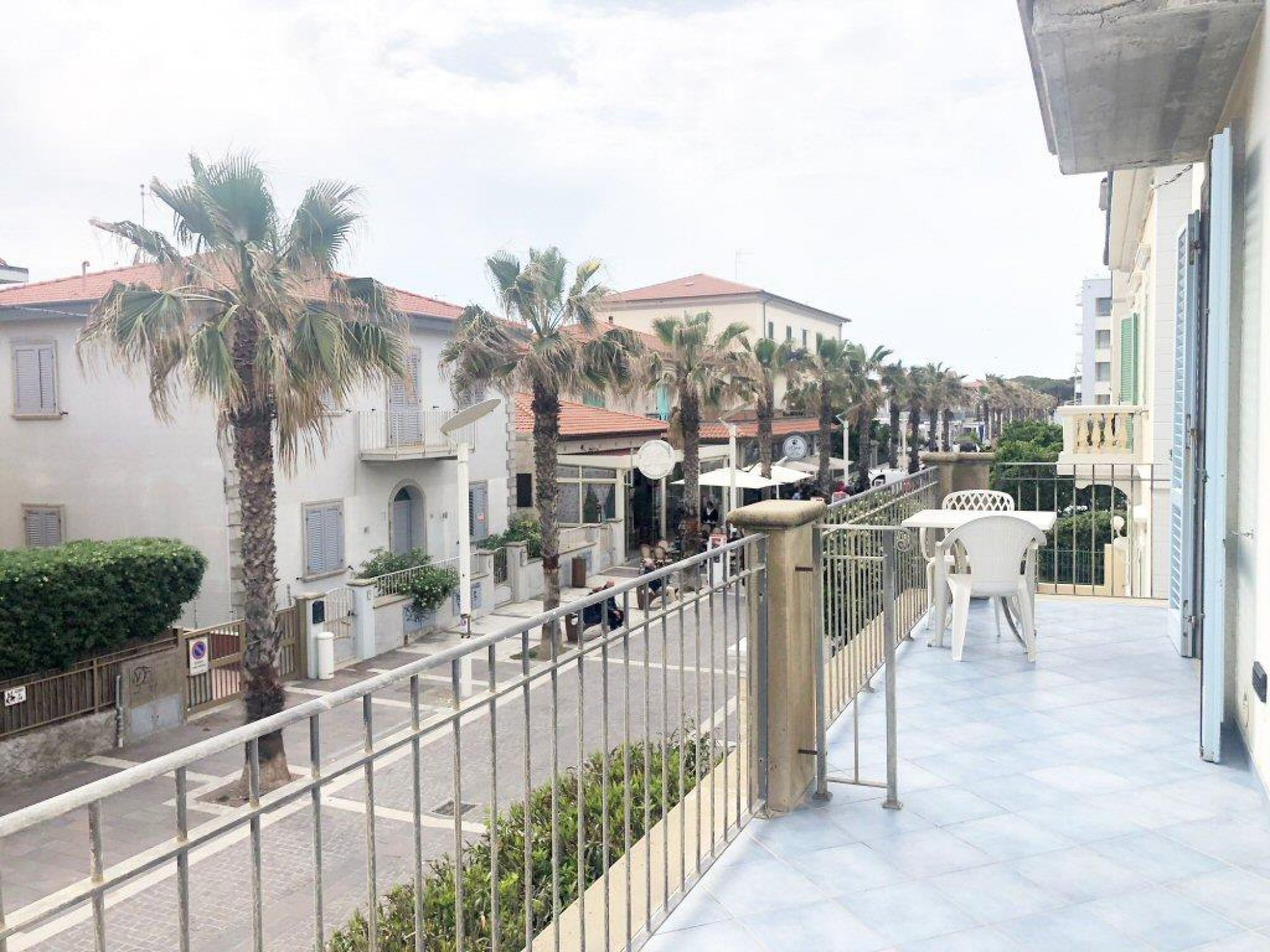 A balcony with a view of a street lined with palm trees and buildings.