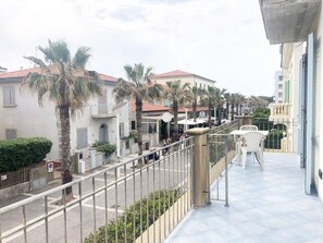 A balcony with a view of a street lined with palm trees and buildings. - Zì Maria (Cecina)