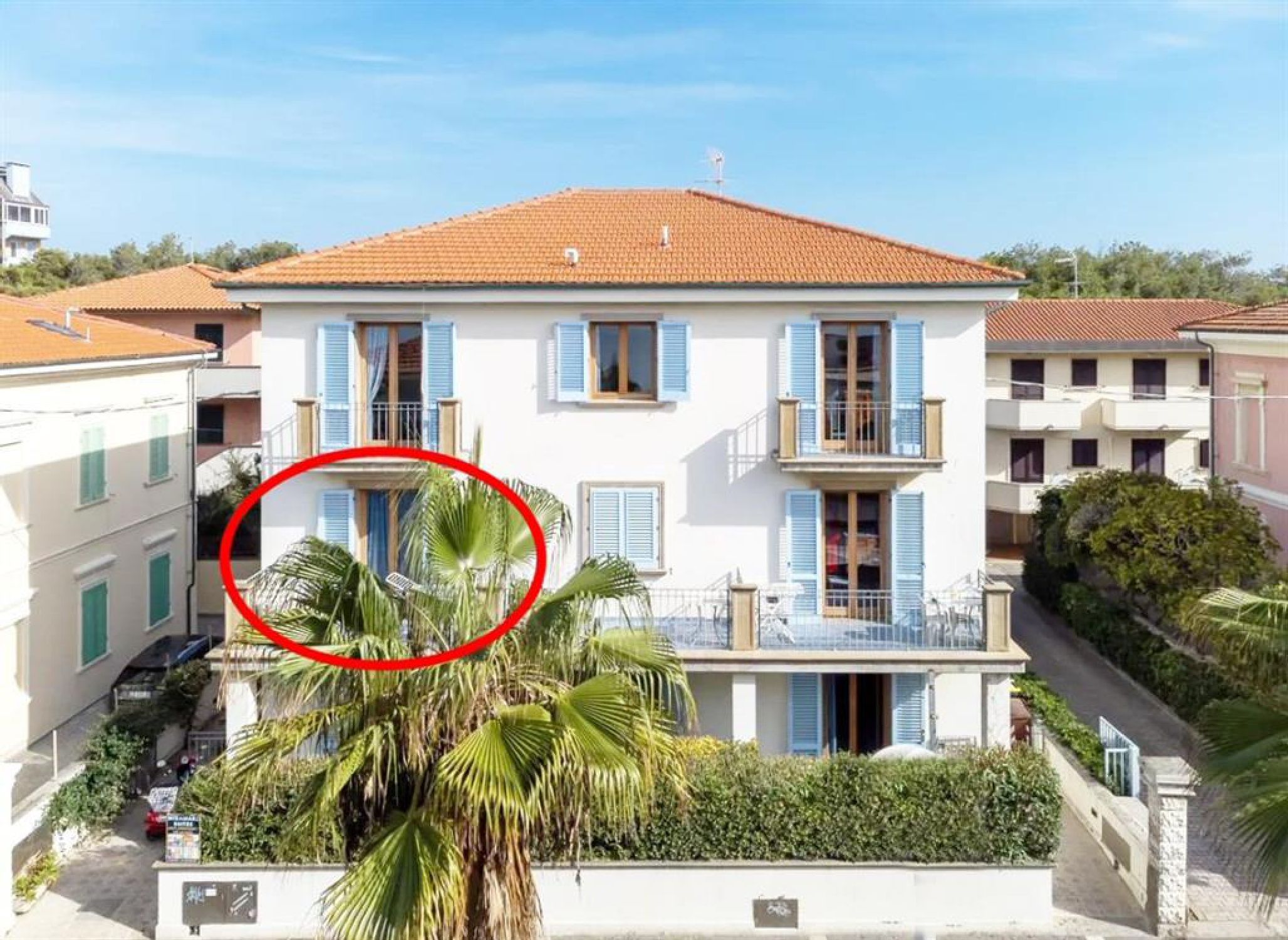 Un edificio a due piani con tetto in tegole rosse, persiane blu e un balcone.