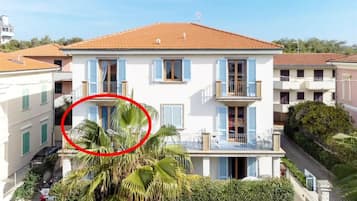 Un edificio a due piani con tetto in tegole rosse, persiane blu e un balcone.