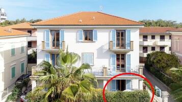 Un edificio a due piani con tetto in tegole rosse, pareti bianche e persiane blu.