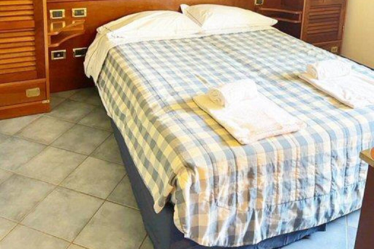 A bedroom with a bed, wooden wardrobe, and a nightstand.