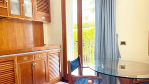 Une pièce avec des meubles de rangement en bois, une table en verre et des chaises bleues.
