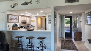 A kitchen with a bar area, white cabinets, and a framed picture on the wall. - Lovely and affordable oceanfront retreat, just steps from St. Augustine Beach (St. Augustine)