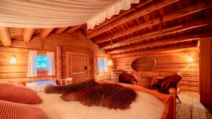 A log cabin room with a large bed, a wooden ceiling, and a rustic ambiance. - Roisheim (Lom)