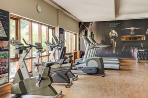 Una palestra con diverse macchine per esercizi, un grande poster appeso al muro e un orologio.