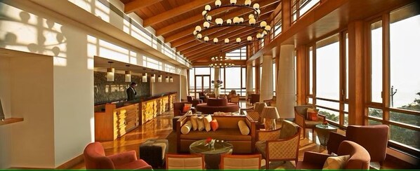 A spacious lobby with a high ceiling, large windows, and a central seating area. - Club Mahindra Resort - Tungi (Ootacamund)