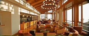 A spacious lobby with a high ceiling, large windows, and a central seating area. - Club Mahindra Resort - Tungi (Ootacamund)