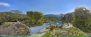 A swimming pool surrounded by lush greenery and mountains in the background. - Club Mahindra Resort - Tungi (Ootacamund)