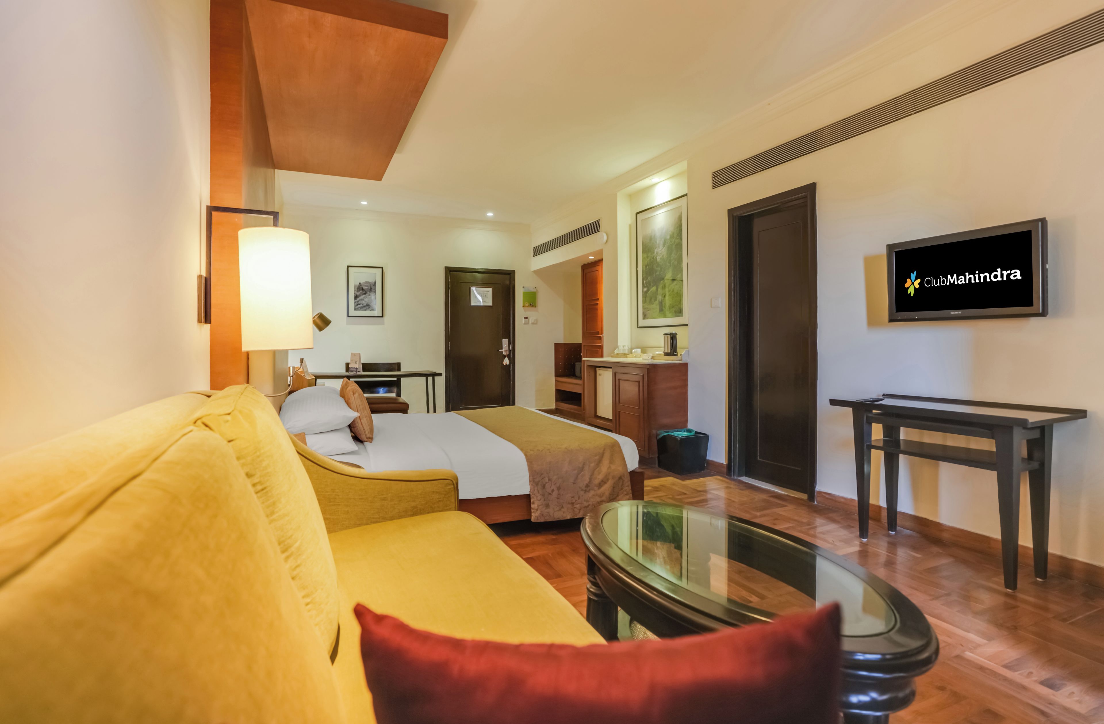 A hotel room with a bed, a sofa, a TV, and a desk.