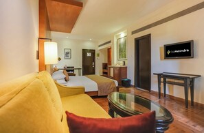 A hotel room with a bed, a sofa, a TV, and a desk. - Club Mahindra Resort - Tungi (Ootacamund)