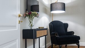 Ein schwarzer Stuhl, eine schwarze Konsole mit einer Blumenvase und eine Stehlampe.