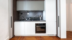 Eine kompakte Küche mit Backofen, Kochfeld und Mikrowelle.