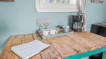 A wooden table with a notebook, a tray with mugs, glasses, and a coffee maker.