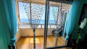 A room with a large window, a wooden floor, and a view of the sea. - VV Miramar Sunset Tabaiba (Tabaiba)