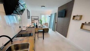 A modern kitchen with a built-in oven, a sink, and a dining area with a table and chairs. - BIMBA Studio Park (La Quinta)
