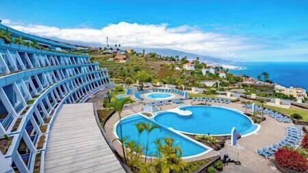 A resort with multiple swimming pools, a wooden deck, and a view of the ocean and hills. - BIMBA Studio Park (La Quinta)