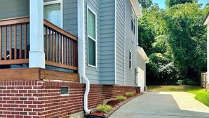 A residential house with a brick foundation, a wooden deck, and a concrete driveway. - ATL Modern Retreat: 3BR, 8 Guests, Near Downtown & Airport (Atlanta)