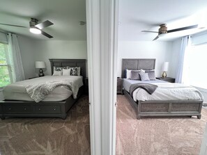 A mirrored bedroom with two beds, a ceiling fan, and a nightstand with a lamp. - ATL Modern Retreat: 3BR, 8 Guests, Near Downtown & Airport (Atlanta)