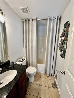 A bathroom with a white toilet, a sink with a dark countertop, a shower with a glass door, and a wall-mounted towel rack. - ATL Modern Retreat: 3BR, 8 Guests, Near Downtown & Airport (Atlanta)