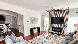 A modern living room with a fireplace, a TV, and a dining area. - ATL Modern Retreat: 3BR, 8 Guests, Near Downtown & Airport (Atlanta)