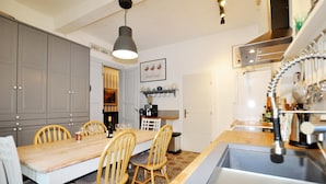 A kitchen with a wooden table, four chairs, a hanging light fixture, and a built-in oven. - Awesome home in Thézan-des-Corbières (Thézan-des-Corbières)