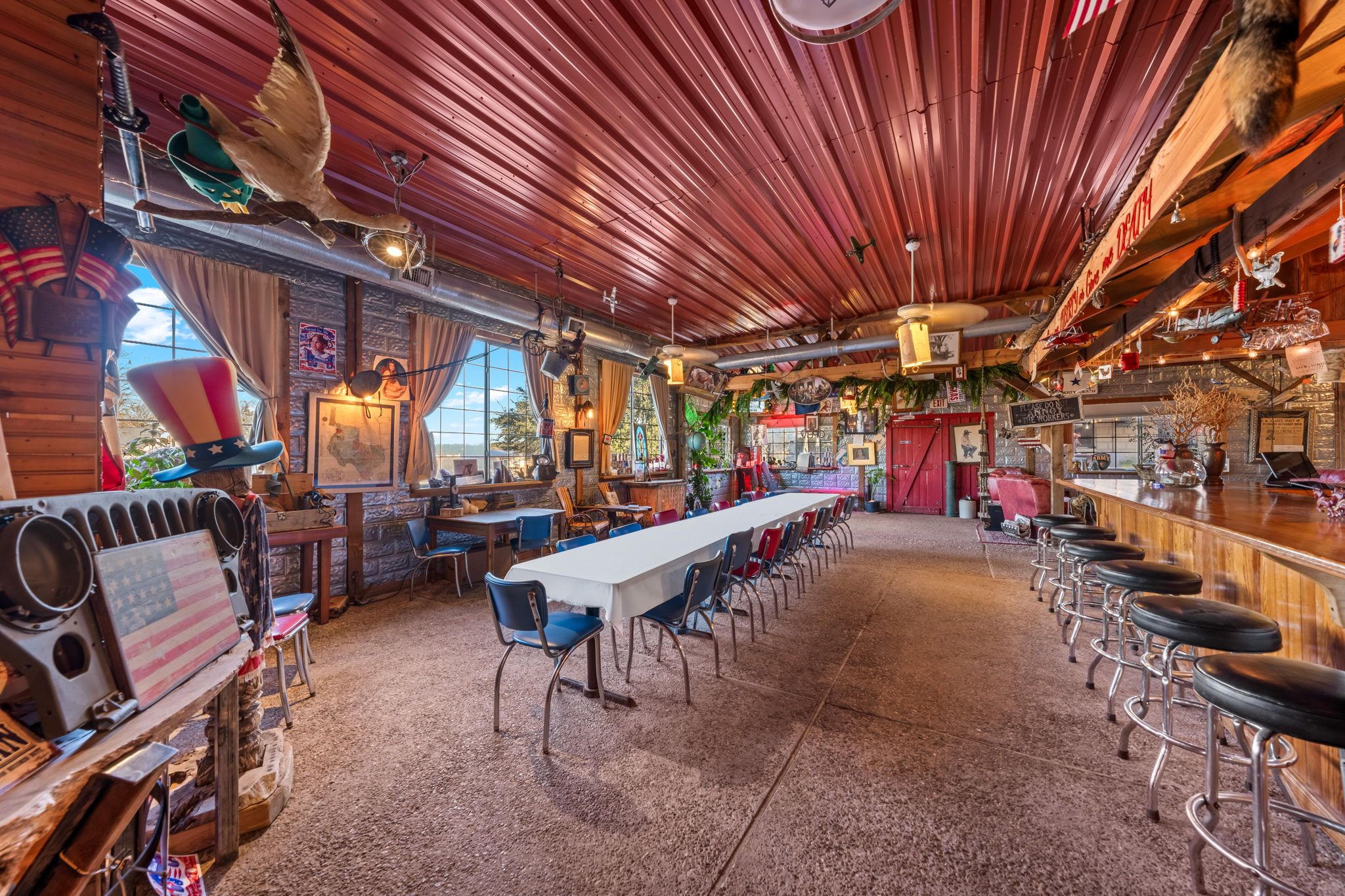 A bar with a long counter and stools, a high ceiling with wooden beams, and a rustic interior with various decorations.