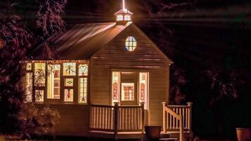 A small church with a cross on the roof, stained glass windows, and a wooden porch.