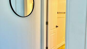 A hallway with a white door, a round mirror on the wall, and a carpeted floor.